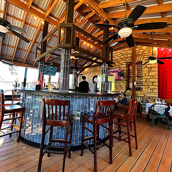 The Barton House of Salado's outdoor bar area with a bartender, blue tiled bar, and wooden ceiling.