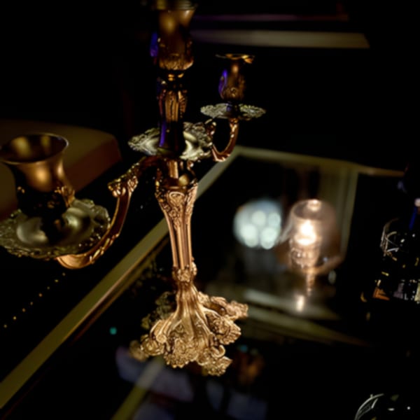 Ornate golden candelabra on a dark table, with soft lights reflecting in the background.