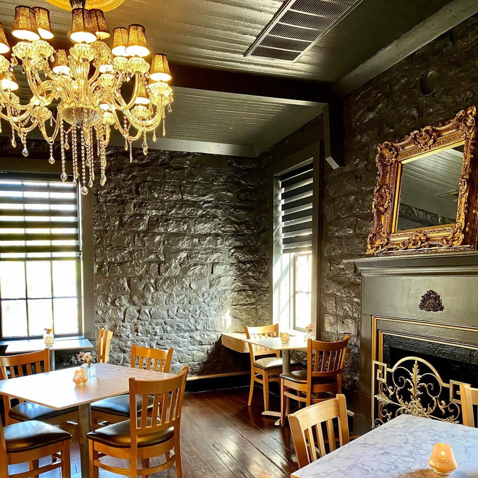 Elegant dining room at The Barton House of Salado with stone walls, chandeliers, and wooden tables.