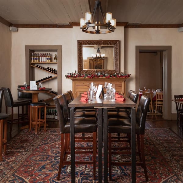 The Barton House of Salado dining room with high-top tables, wine racks, and a decorative fireplace.