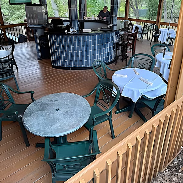 Outdoor patio dining area at The Barton House of Salado, with tables, chairs, and a bar.
