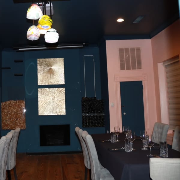 A dining room at The Barton House of Salado with a set table, modern art, and colorful light fixtures.